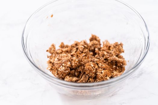 Mixing ingredients in a large glass mixing bowl to prepare cinnamon crumb topping.