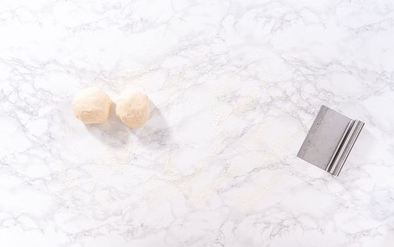 Flat lay. Rolling pizza dough with a french rolling pin to prepare cinnamon dessert pizza.