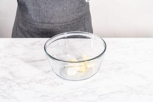 Mixing ingredients in a large glass mixing bowl to prepare cream cheese drizzle sauce.