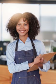 Young Female manager in restaurant with notebook. Woman coffee shop owner with open sign. Small business concept.