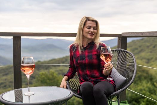 Young woman with glass of wine in peaceful mountains.