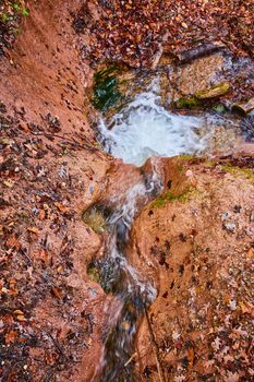 Image of Small creek going through brown clay carving out patterns