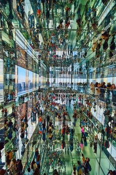 Image of Vertical room of hundreds of tourists reflecting in mirrors everywhere in skyscraper overlooking New York City