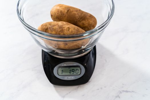 Pressure Cooker Baked Potatoes. Measuring raw potatoes in a glass mixing bowl on the kitchen scale.