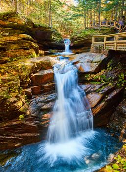 Image of Stunning wide view of New Hampshire waterfalls tucked into lush fall forest and boardwalk overlooks for tourists