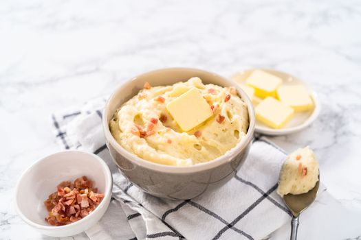 Mashed potatoes. Creamy mashed potatoes garnished with a slice of butter and bacon bits in a bowl.