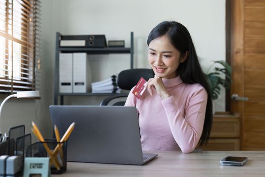 Young person using credit card and laptop computer. Online shopping, e-commerce concept.