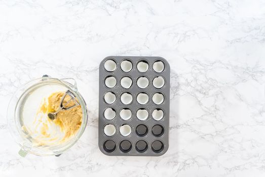 Flat lay. Scooping cupcake batter with dough scoop into a baking pan with liners to bake American flag mini cupcakes.