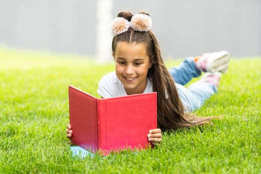 Cute Little Girl Reading Book Outside on Grass.