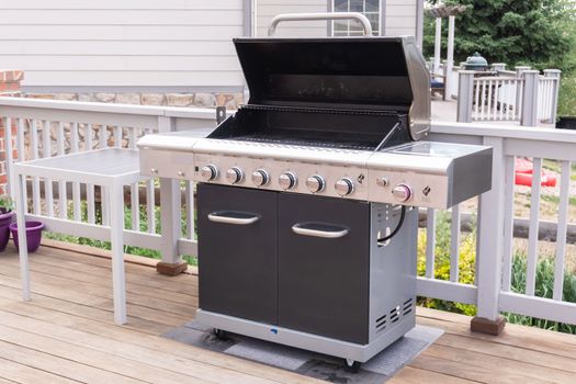 Outdoor six-burner gas grill on the back patio of a luxury single-family home.