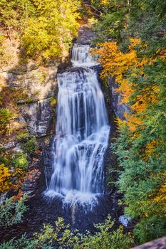 Image of Vertical close of large waterfall from above surrounded by cliffs and fall forests