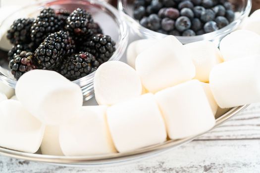 Arranging fruit s'mores charcuterie board on a white tray.