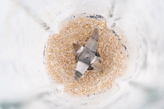 Blending ingredients for healthy breakfast strawberry banana smoothie in a kitchen blender.