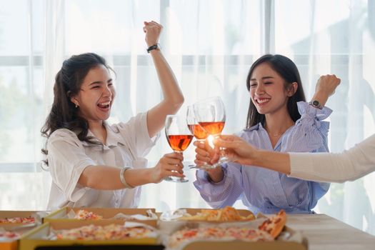 Friends at birthday party clinking glasses with champagne and pizza, enjoying Christmas vacation, pizza on the table. Holiday Party event.