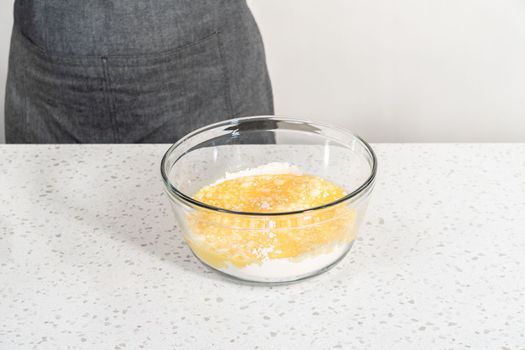 Mixing wet ingredients in a small glass mixing bowl to bake a simple vanilla bundt cake.