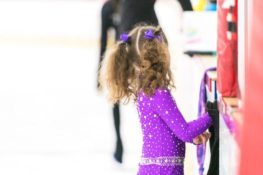 Little girl practicing figure skating on an indoor ice skating rink.