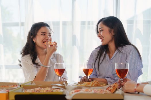 Friends at birthday party clinking glasses with champagne and pizza, enjoying Christmas vacation, pizza on the table. Holiday Party event.