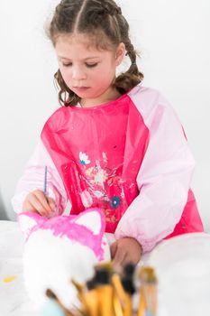 Little girl painting Halloween pumpkin with acrylic paint.