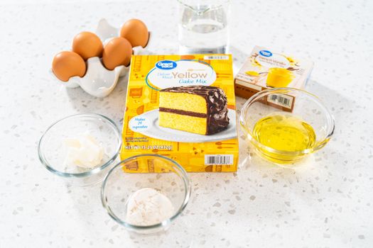 Measured ingredients in glass mixing bowls to bake a simple vanilla bundt cake from a box cake.