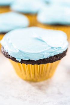 Decorating chocolate cupcakes with buttercream frosting and rainbow candy.