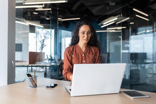 Cheerful and successful indian woman programmer at work inside modern office, tech support worker with laptop typing on keyboard smiling.