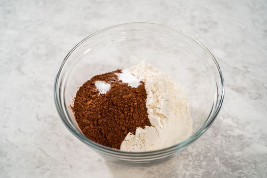Mixing ingredients in a large glass mixing bowl to bake chocolate cookies with peppermint chips.