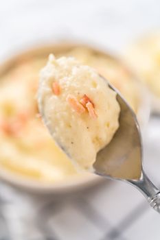 Mashed potatoes. Creamy mashed potatoes garnished with a slice of butter and bacon bits in a bowl.