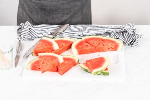Slicing riped red watermelon to prepare chili lime watermelon pops.