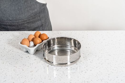 Filling metal pressure cooker insert with raw eggs to cook boiled eggs for potato salad.
