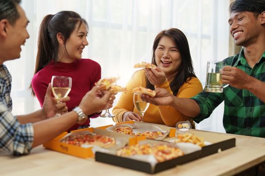 Friends at birthday party clinking glasses with champagne and pizza, enjoying Christmas vacation, pizza on the table. Holiday Party event