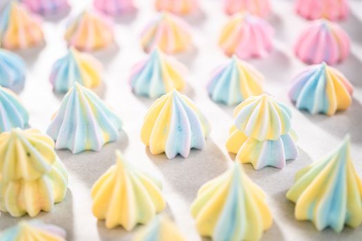 Freshly baked unicorn meringue cookies on a baking sheet with a parchment paper.