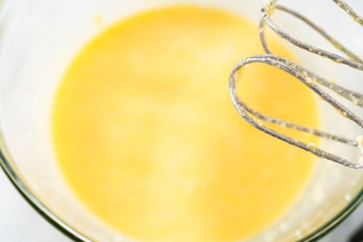 Mixing ingredients in a large glass mixing bowl to bake red velvet bundt cake with cream cheese glaze.