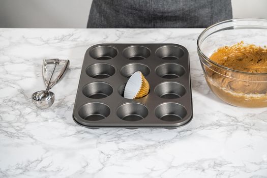 Lining cupcake pan with foil cupcake liners to bake gingerbread cupcakes.