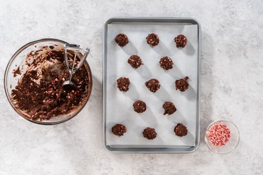 Flat lay. Scooping chocolate cookie dough with dough scoop to bake chocolate cookies with peppermint chips.