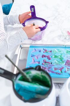 Filling silicone chocolate molds with melted chocolate to make chocolate mermaid tails.