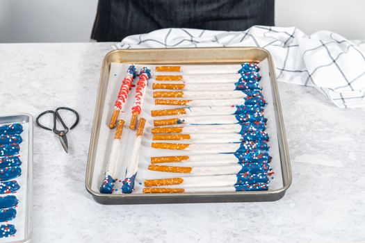 Dipping pretzel rods into the melted chocolate to prepare chocolate dipped pretzel rods for the July 4th celebration.