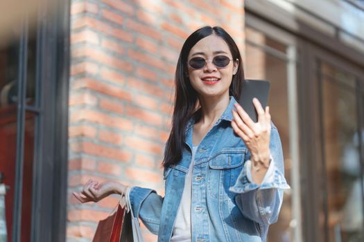 Asian fashionable woman walking at shopping mall with shopping bags while flash sale promotion.