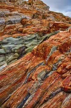 Image of Rock layers cover coast of Maine with orange layers and quarter veins