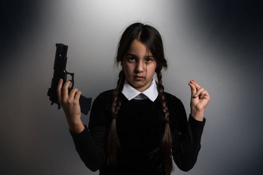 A girl with braids in a gothic style on a dark background with weapons.