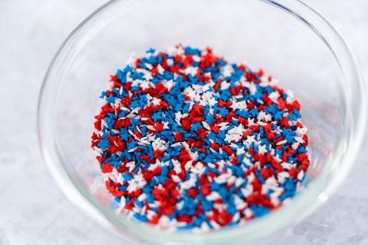 Star-shaped white, red, and blue sprinkles in a glass pinch bowl.