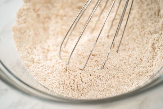 Mixing ingredients in a large glass mixing bowl to bake gingerbread cupcakes.