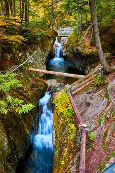 Image of Beautiful waterfall in narrow gorge with fence along overlook during fall