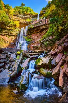 Image of Stunning terraced waterfalls small and large from below over mossy rocks surrounded by New York fall foliage