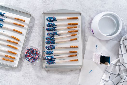 Flat lay. Dipping pretzel rods into the melted chocolate to prepare chocolate dipped pretzel rods for the July 4th celebration.