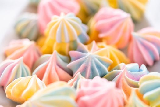 Multicolored unicorn meringue cookies on a white serving plate.