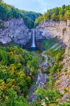Image of Giant canyon with large waterfall flowing into it and surrounded by fall forests