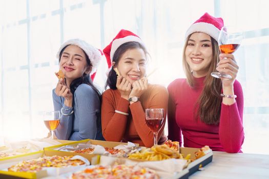 Friends at birthday party clinking glasses with champagne and pizza, enjoying Christmas vacation, pizza on the table. Holiday Party event.