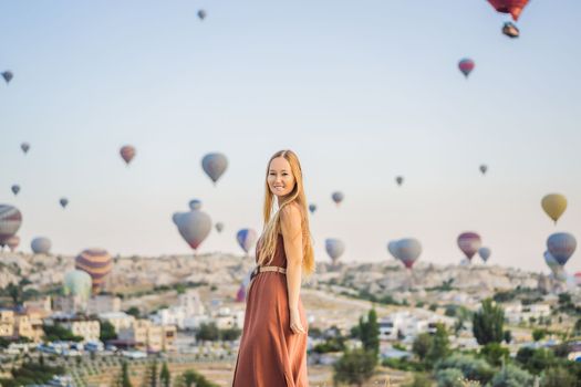 Tourist woman looking at hot air balloons in Cappadocia, Turkey. Happy Travel in Turkey concept. Woman on a mountain top enjoying wonderful view.