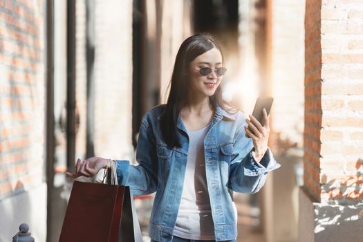 Asian fashionable woman walking at shopping mall with shopping bags while flash sale promotion.