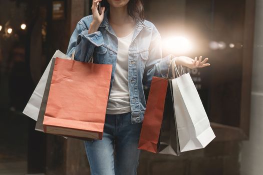 Asian fashionable woman walking at shopping mall with shopping bags while flash sale promotion.